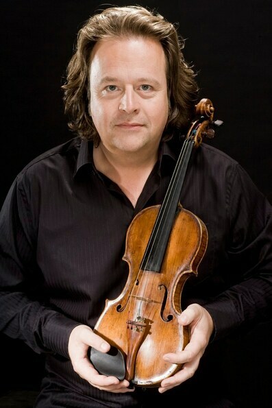 Poträt des Violinisten Gernot Süßmuth in schwarzem Hemd. Er hält in den Händen eine Geige vor einem schwarzen Hintergrund.