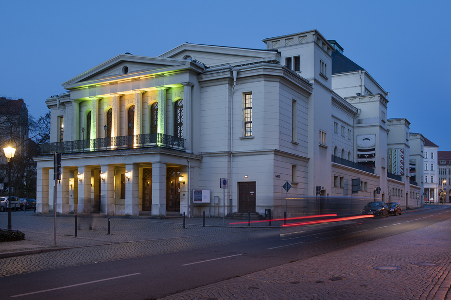 Historisches Theatergebäude in Görlitz am Abend, mit klassizistischer Architektur, beleuchteter Fassade und vorbeifahrenden Autos mit Lichtspuren