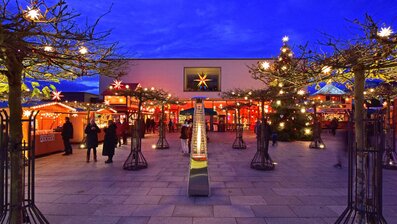 Stimmungsvoller Weihnachtsmarkt bei Abenddämmerung mit festlicher Beleuchtung