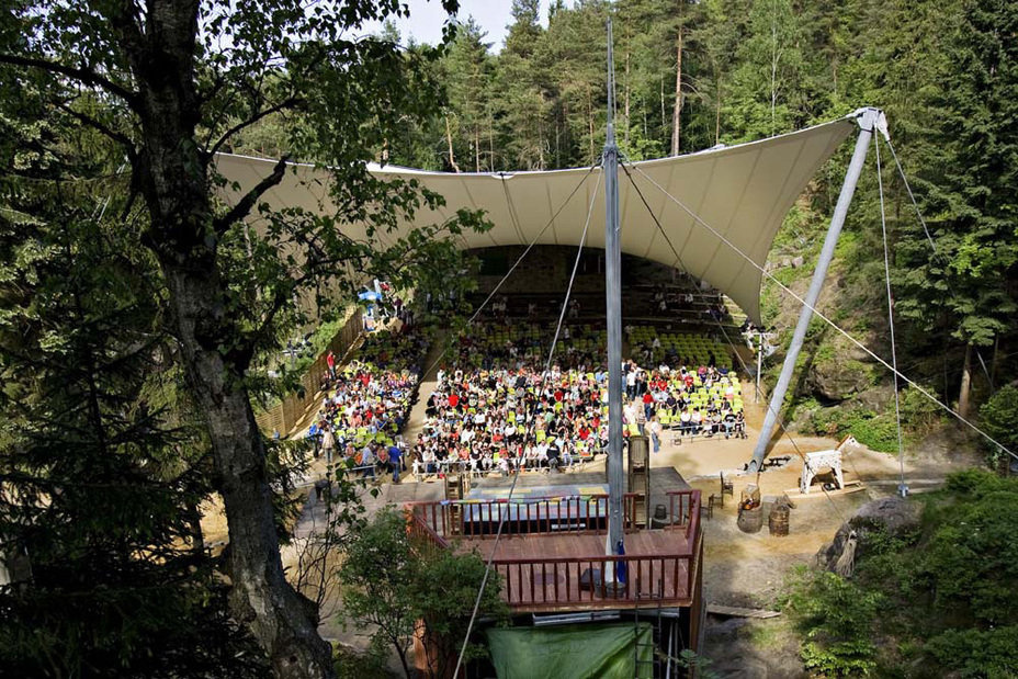 Open-Air-Theater Waldbühne Jonsdorf, umgeben von Wald, mit gespanntem Publikum unter einem großen, weißen Zeltdach
