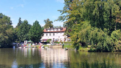 Idyllischer See mit historischem Gebäude im Grünen
